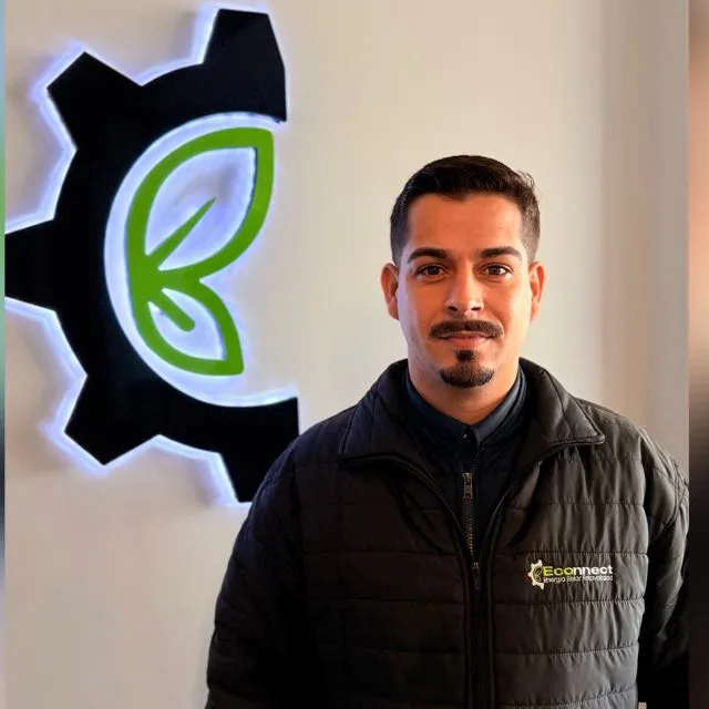 Juliano Lamas, consultor de energia solar, de jaqueta Econnect em frente ao letreiro luminoso com a marca da empresa