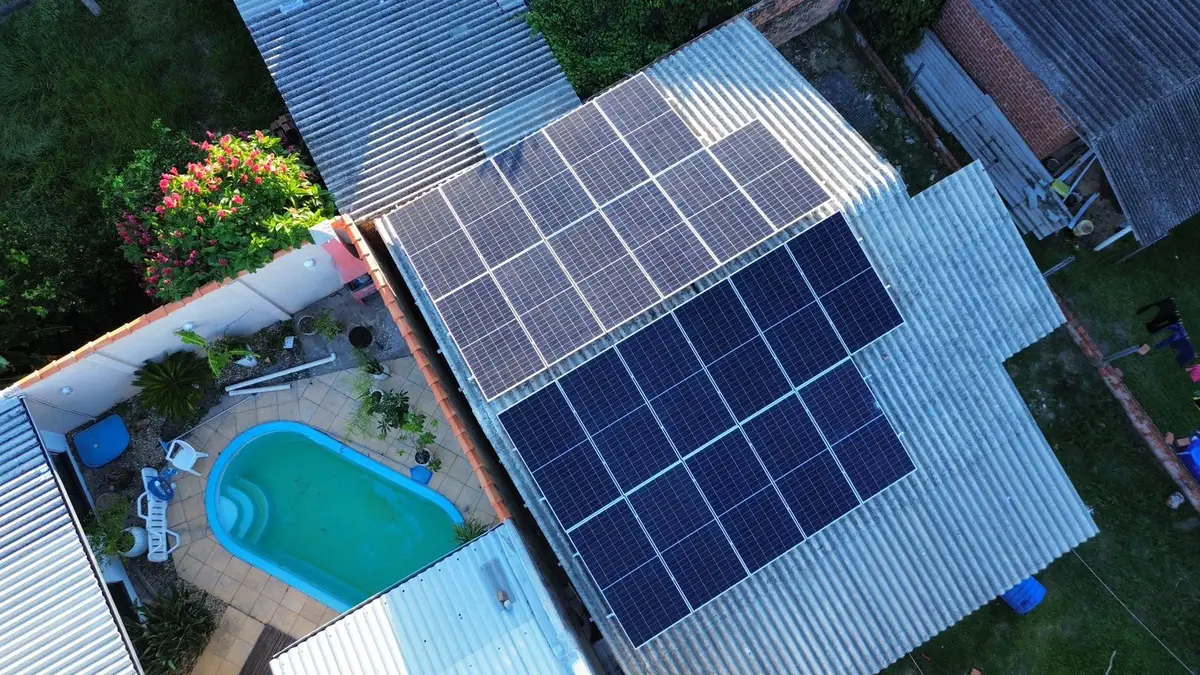 Vista aérea de residência com piscina e módulos fotovoltaicos instalados no telhado